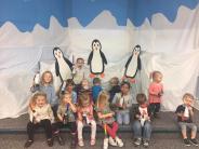 Children Holding Penguins in Front of Arctic Background