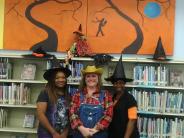 Two Witches and a Scarecrow Standing in Front of Halloween Trees Background